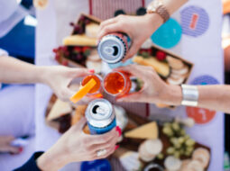 Cans and glasses coming together for Cheers celebrating beverage alcohol growth. View from the sky looking down