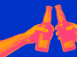 two non-descript bottles held by hands doing cheers to symbolize brand building in beverage alcohol