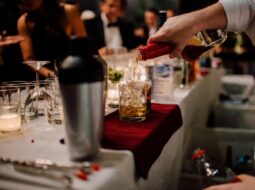 View from the back bar looking past the bartender pouring drinks and onto the crowd at the bar.