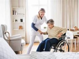 caregiver providing help to a senior struggling to get out of a wheel chair